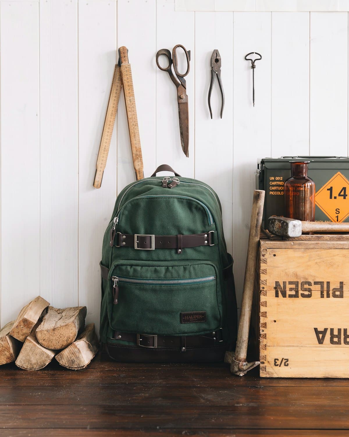 A dark green backpack beside tools on a wooden floor