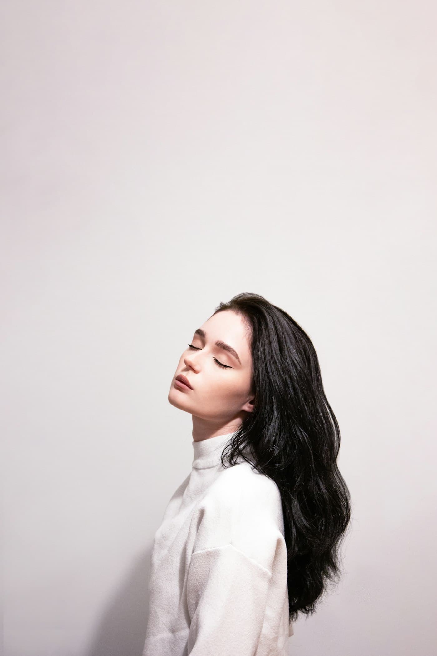 Woman in a white high-neck top in soft studio light