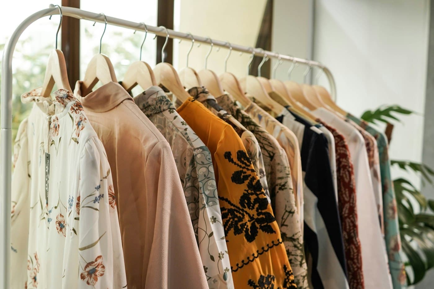 A rail of printed blouses on wooden hangers