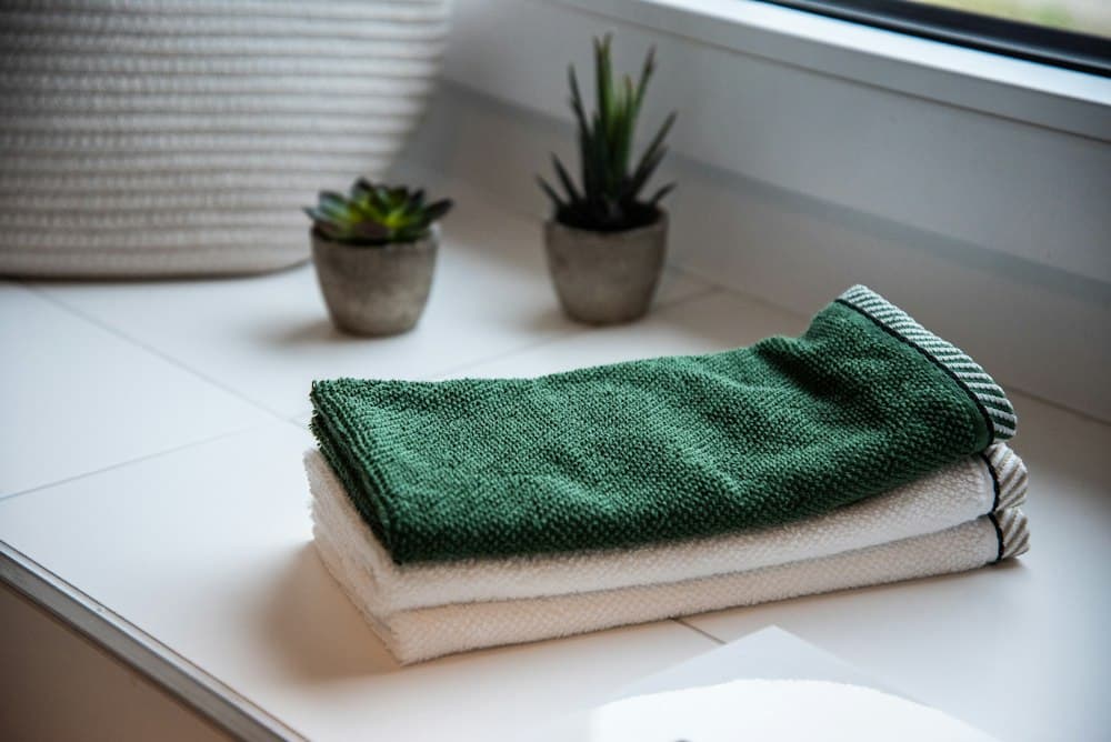 Folded green towel on a bath ledge
