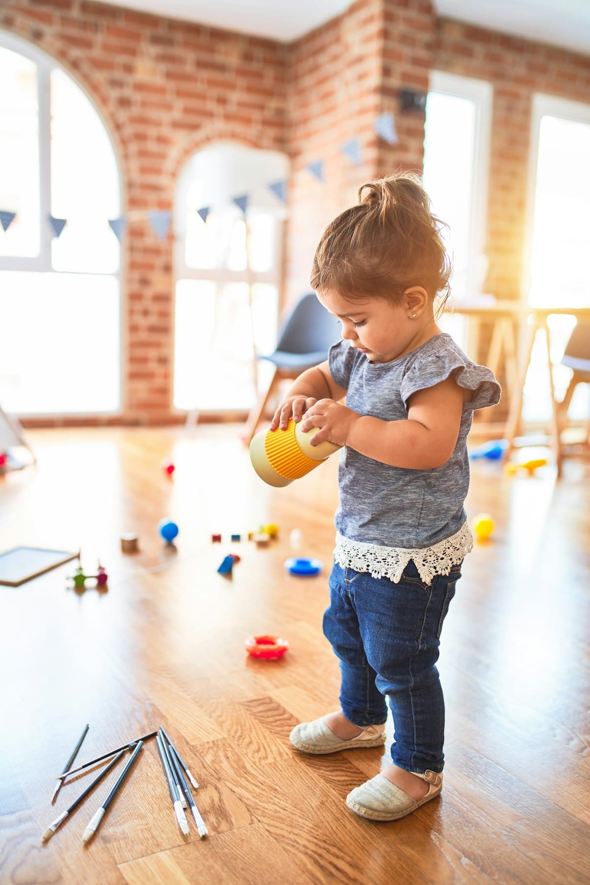 A toddler playing with toys on a sunny wooden floor