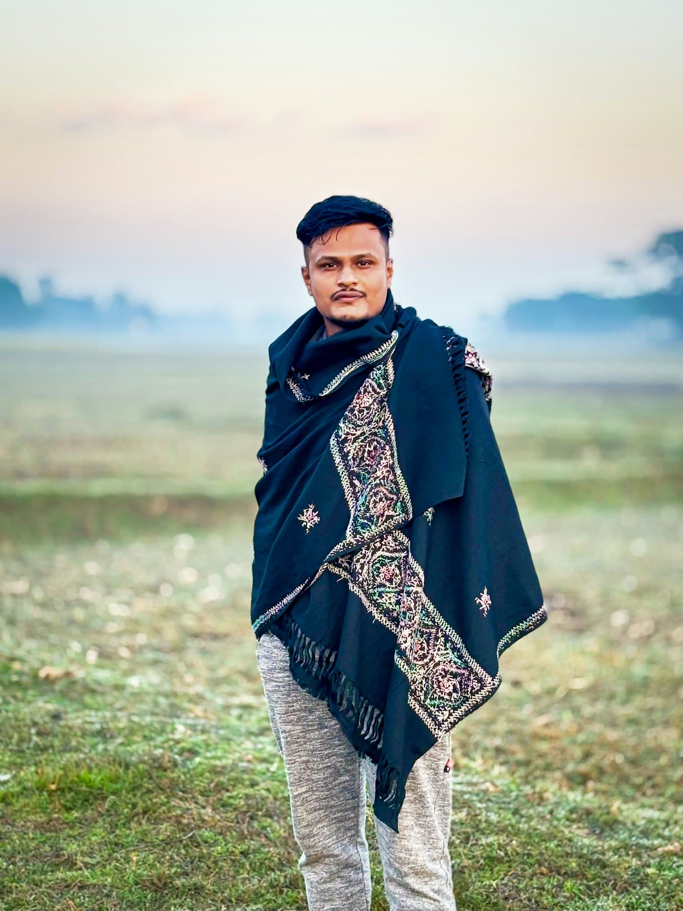 A man wrapped in a navy embroidered wool shawl on a misty winter morning