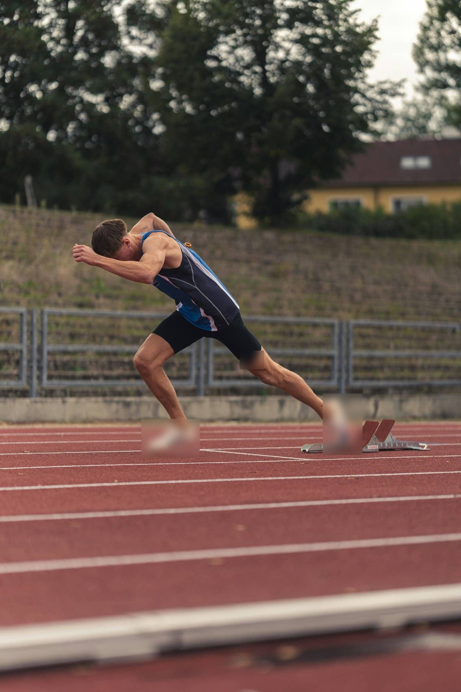 A sprinter driving out of the starting blocks on a red track