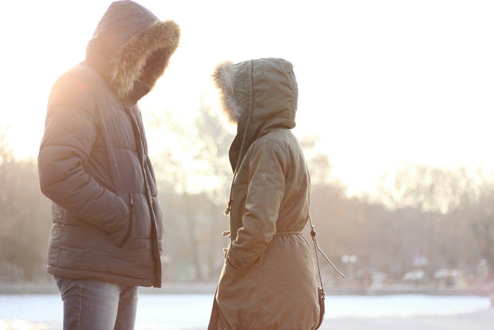 Two people in hooded winter coats at sunset